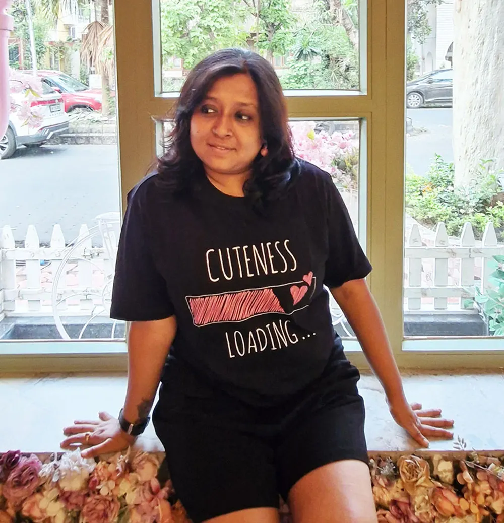 Woman wearing Black themed Cuteness Loading T-shirt and sitting in the cafe