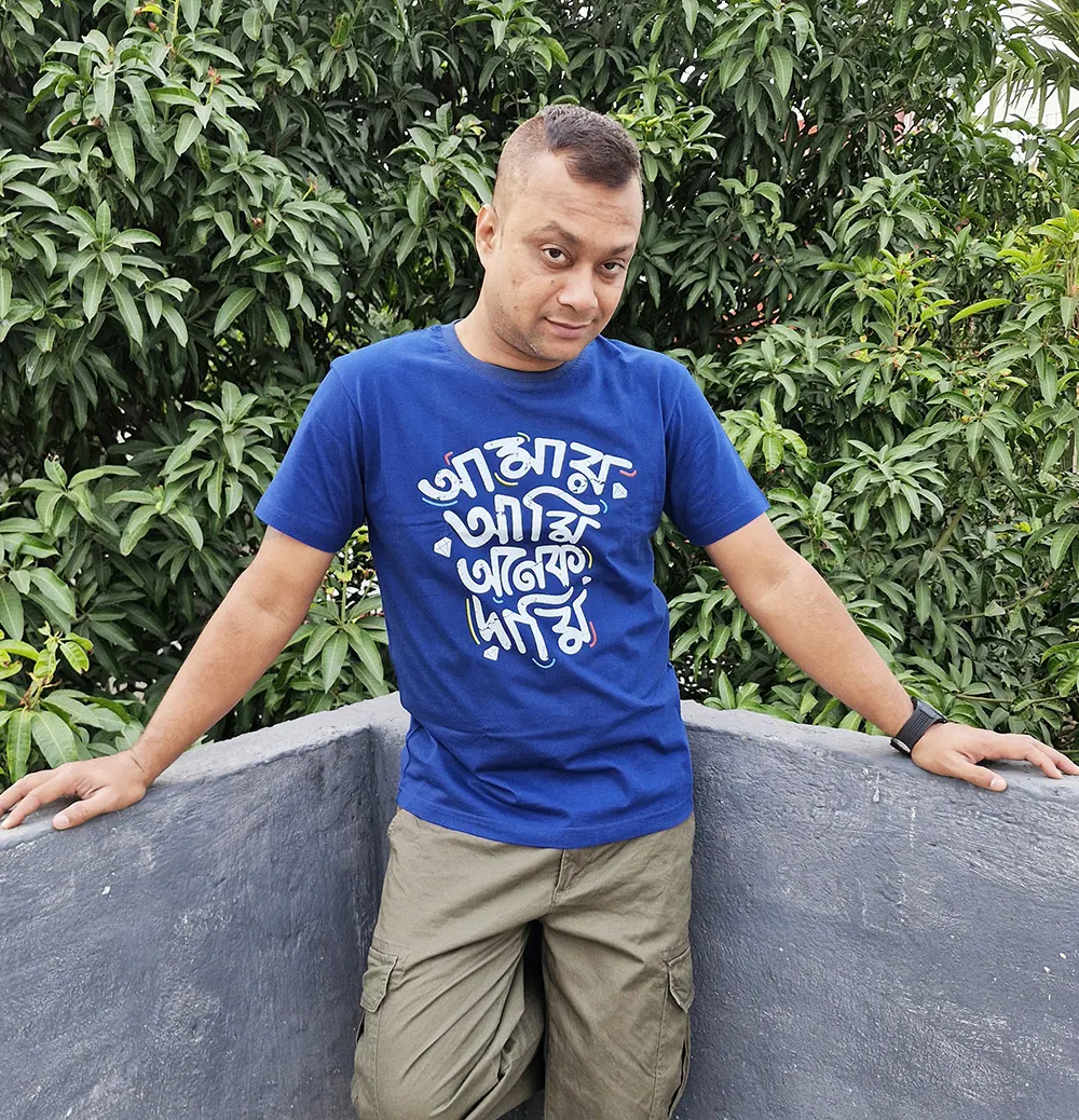 Man wearing Amar Ami Anem Dami Bengali themed T-shirt on a terrace
